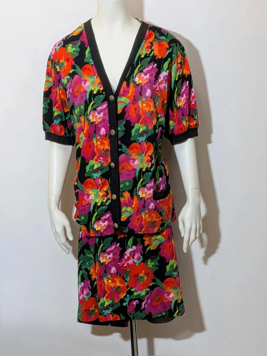 Leda Grotte black floral skirt suit with gold buttons and short balloon sleeves.