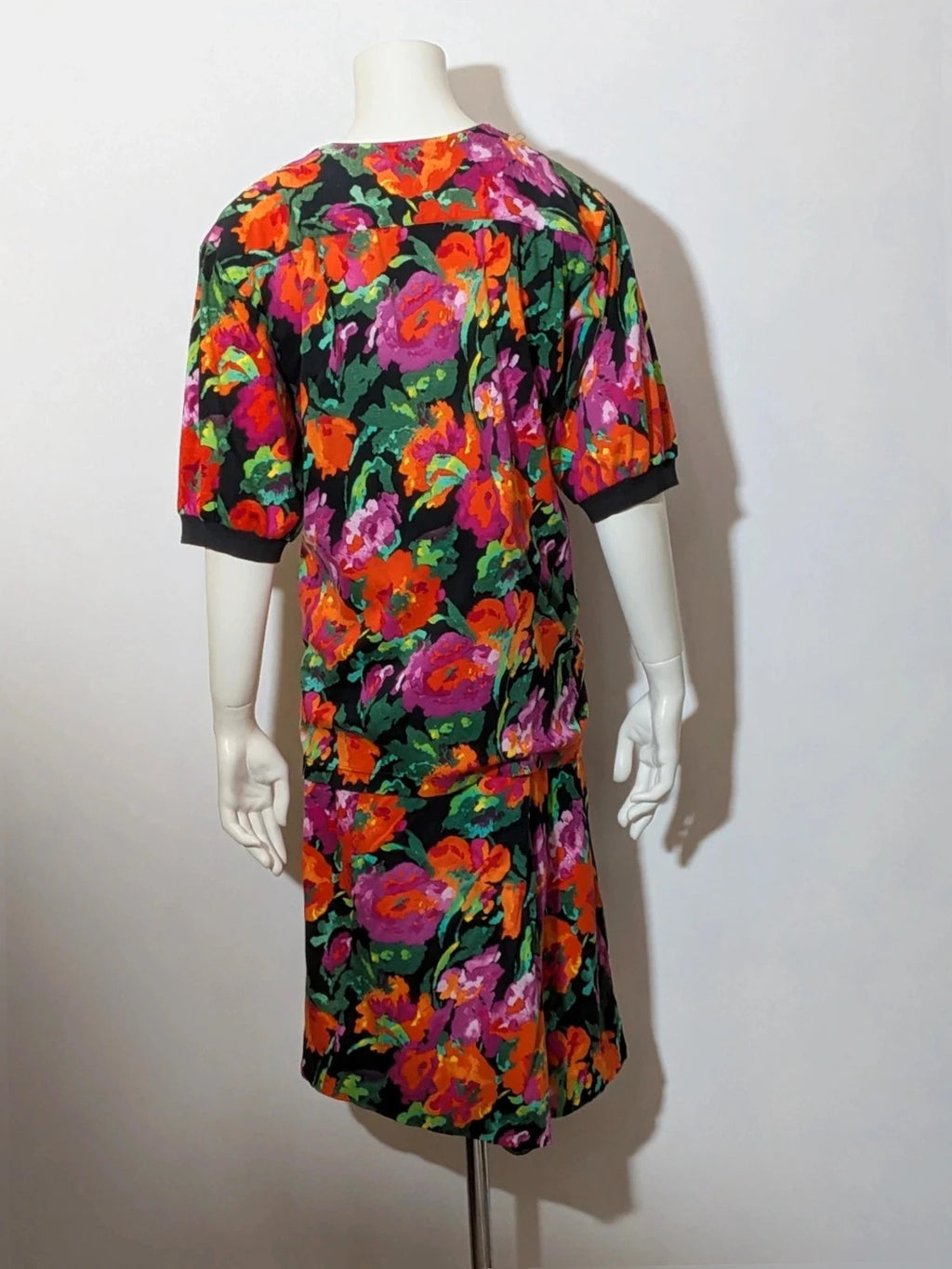Leda Grotte black floral skirt suit with gold buttons and short balloon sleeves.