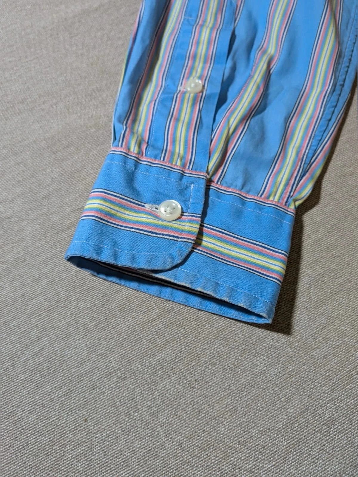 Polo Ralph Lauren multicolor striped shirt with pink pony logo on sky blue background.