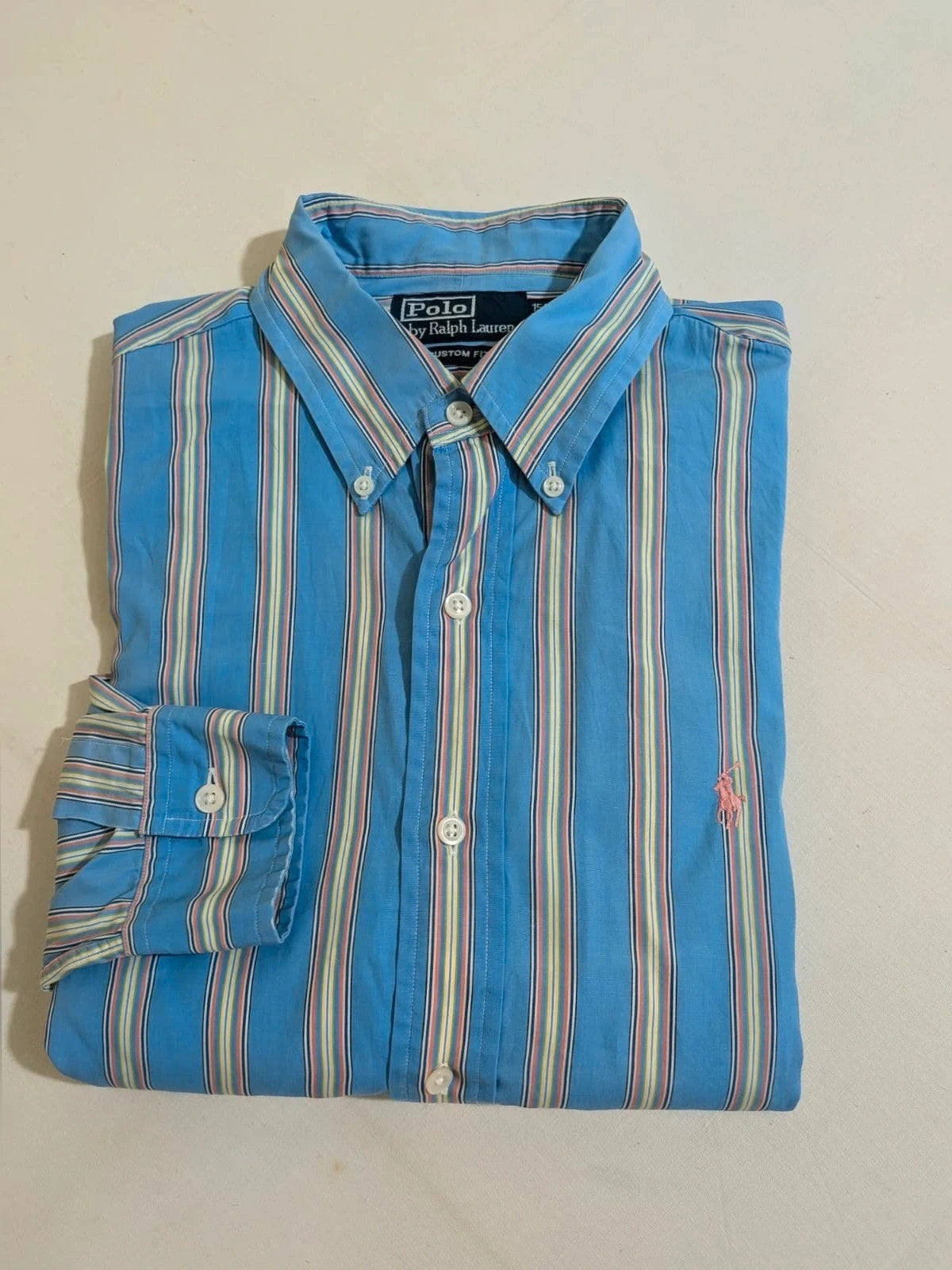 Polo Ralph Lauren multicolor striped shirt with pink pony logo on sky blue background.