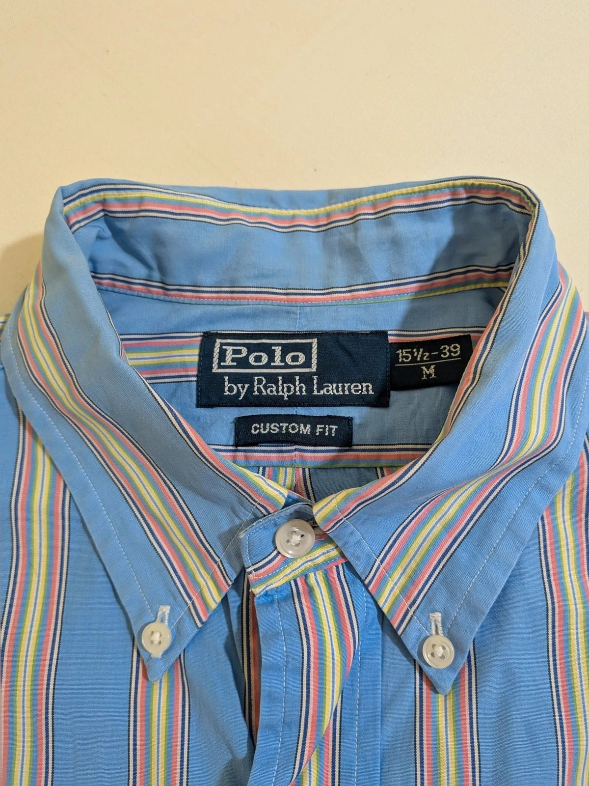 Polo Ralph Lauren multicolor striped shirt with pink pony logo on sky blue background.
