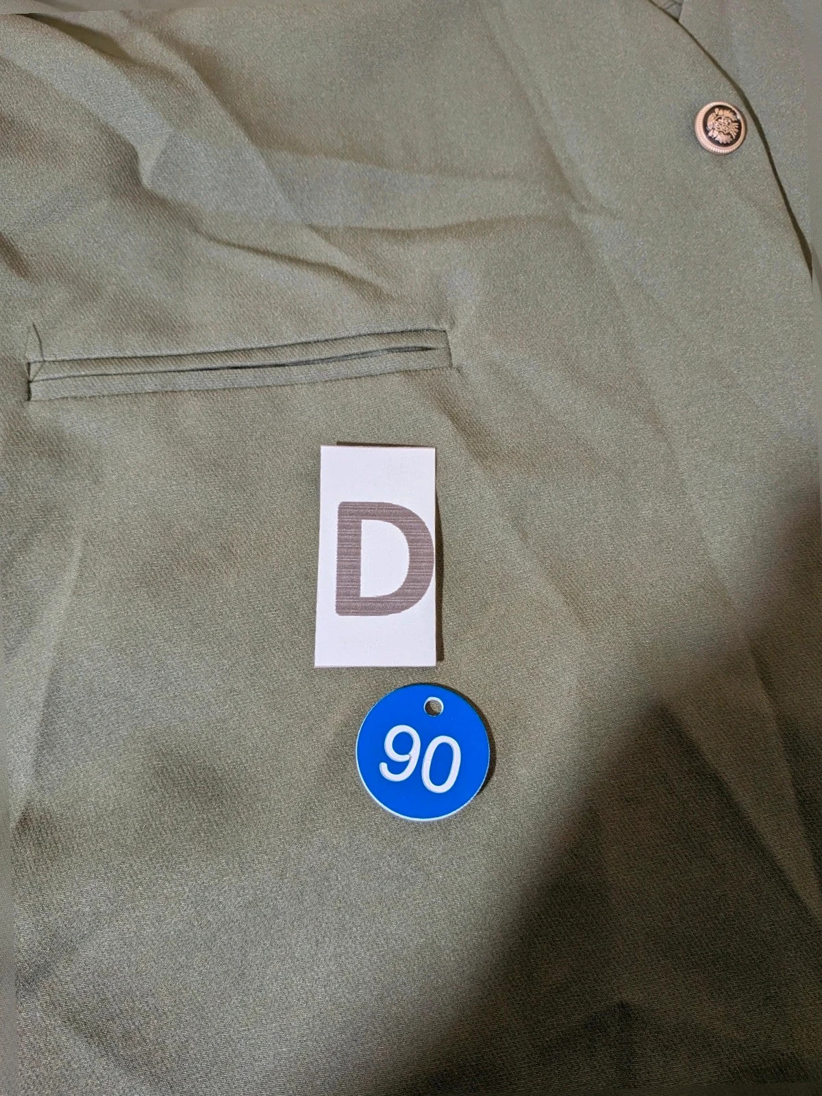 Adon green suit with gold jewel button and embossed heraldic emblem.