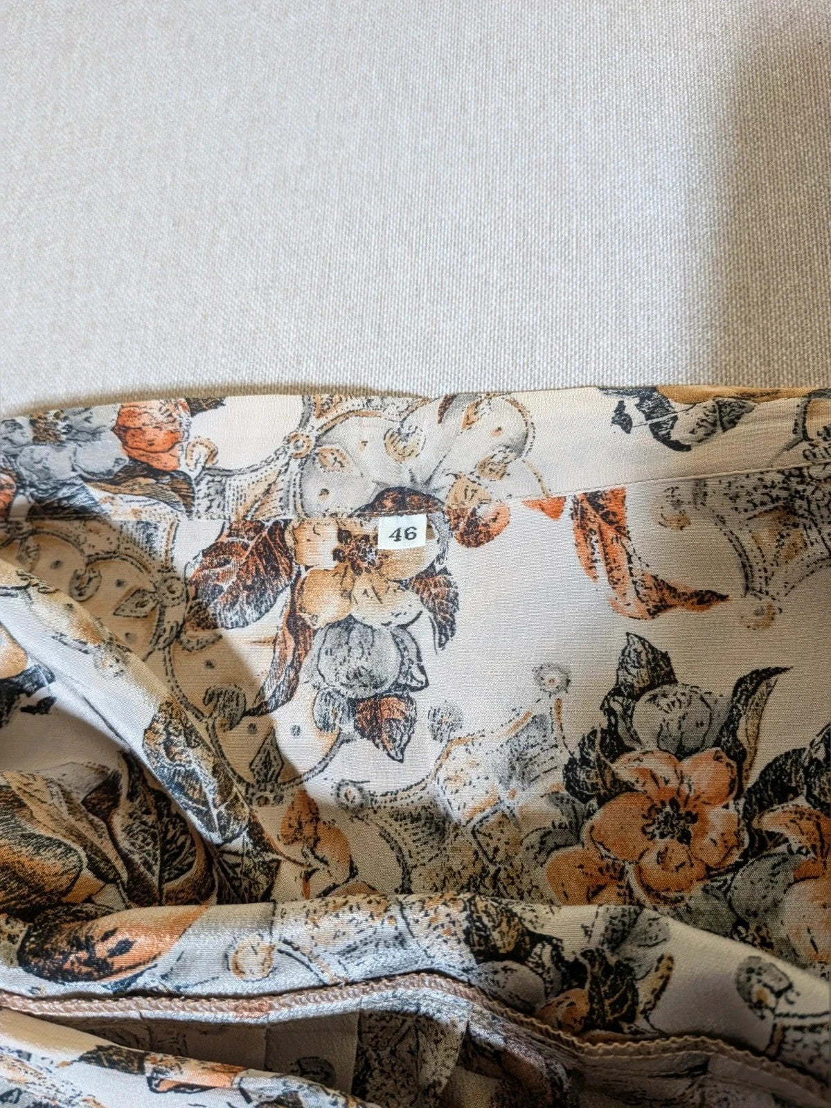 Bellissima beige floral print skirt suit with V-neck blouse and pleated midi skirt.
