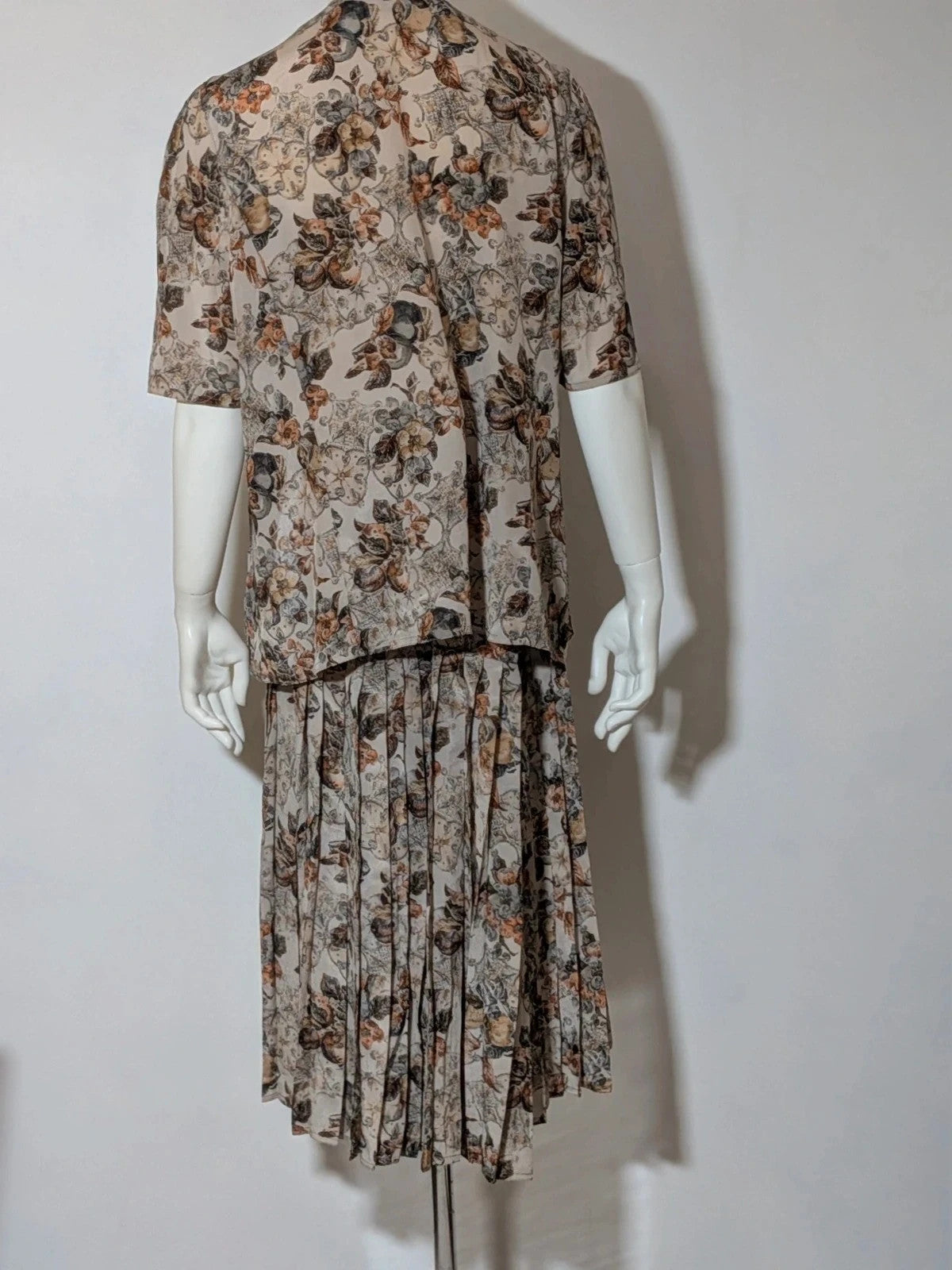 Bellissima beige floral print skirt suit with V-neck blouse and pleated midi skirt.