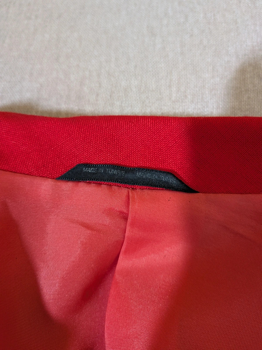 Tessuto red skirt suit with double-breasted jacket and linen-like texture.