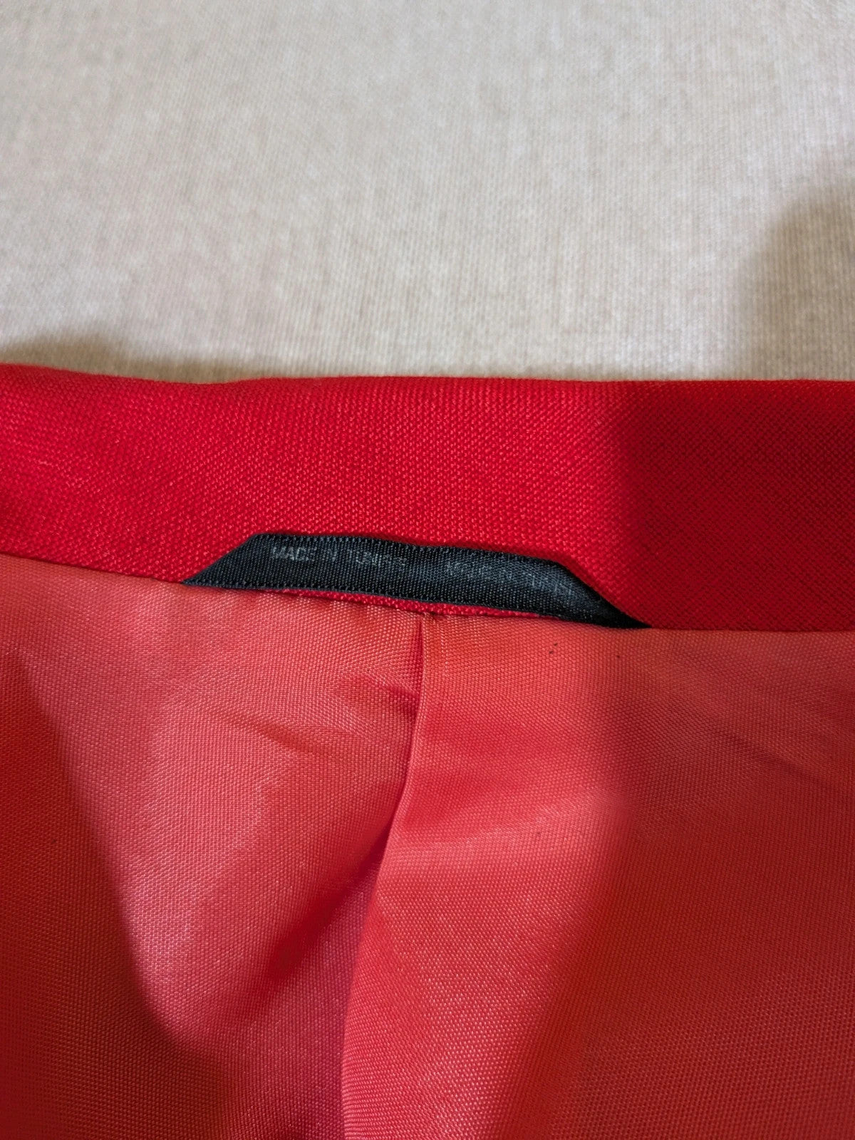 Tessuto red skirt suit with double-breasted jacket and linen-like texture.