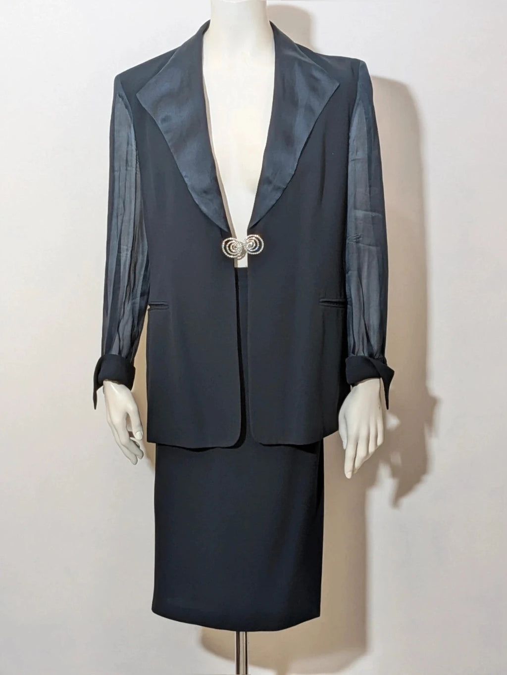Blazer black skirt suit with navy satin lapels and sheer chiffon sleeves, jeweled clasp detail.