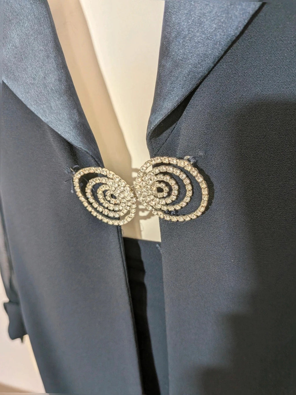 Blazer black skirt suit with navy satin lapels and sheer chiffon sleeves, jeweled clasp detail.