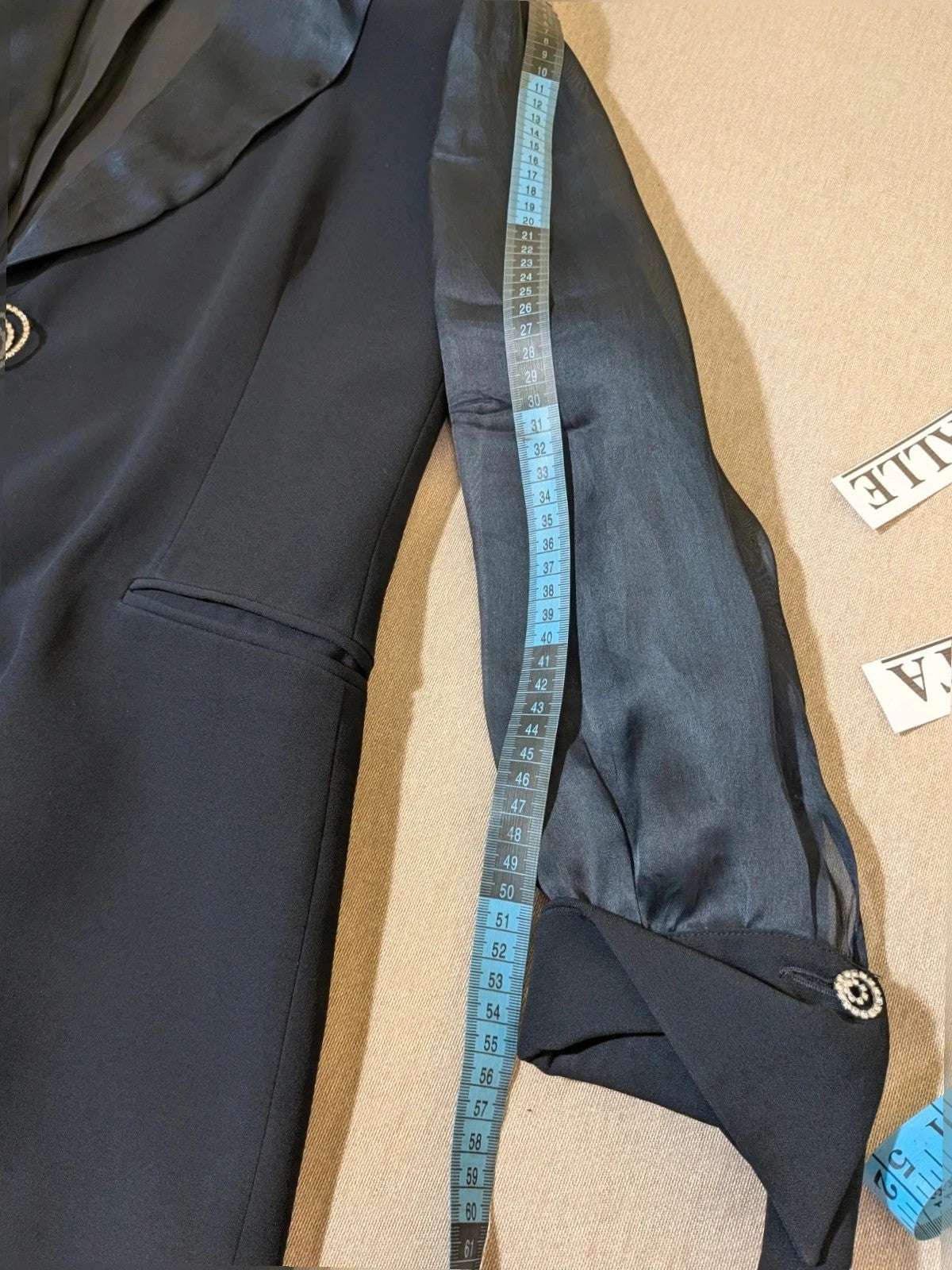 Blazer black skirt suit with navy satin lapels and sheer chiffon sleeves, jeweled clasp detail.