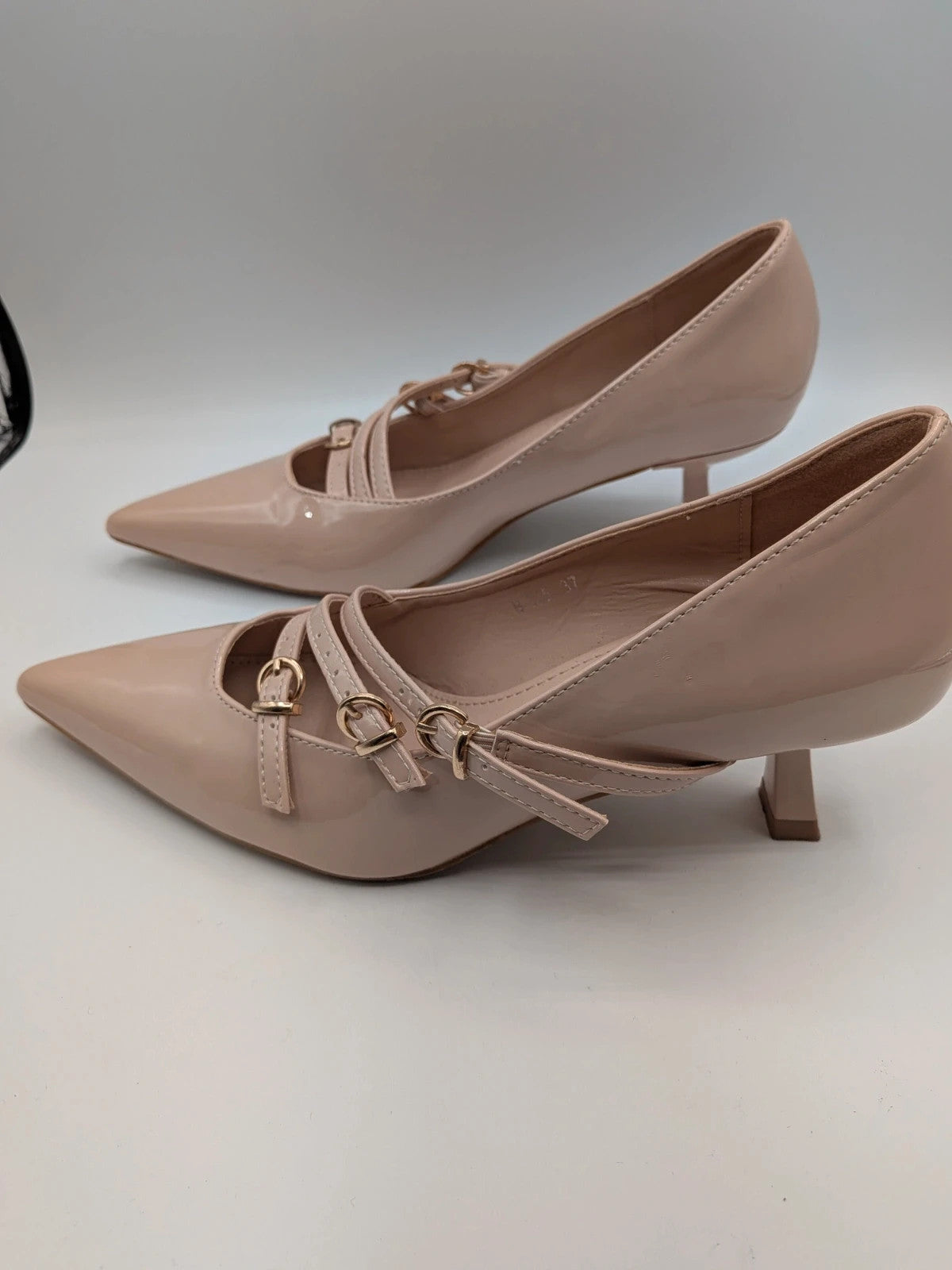 Mix Feel beige heels with pointed toe, glossy patent finish, and decorative gold buckles.