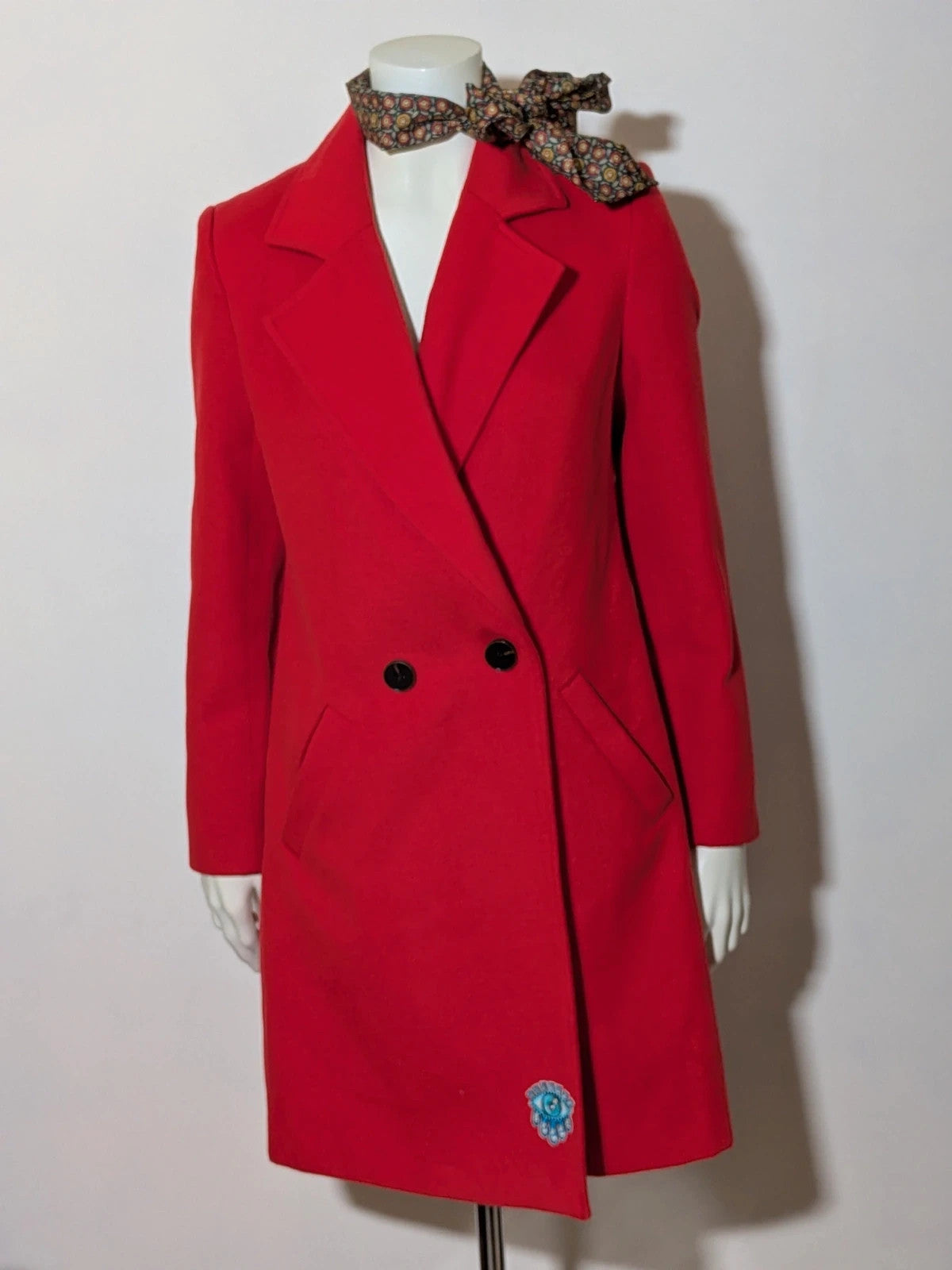 Studio F red coat with black button closure and gold logo tag on collar.