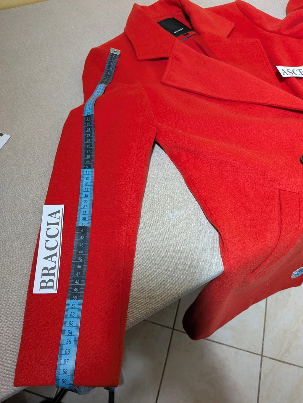 Studio F red coat with black button closure and gold logo tag on collar.