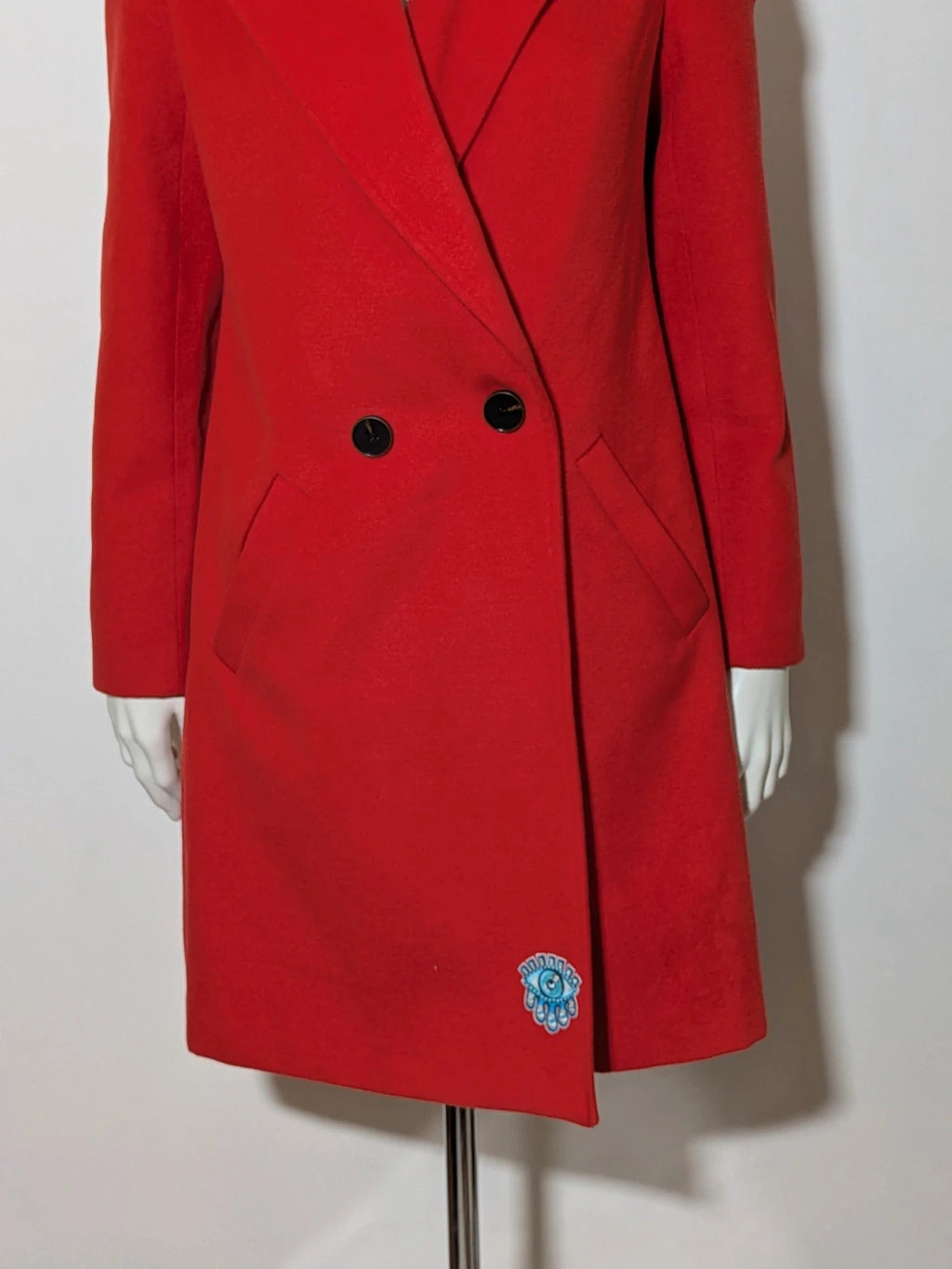 Studio F red coat with black button closure and gold logo tag on collar.