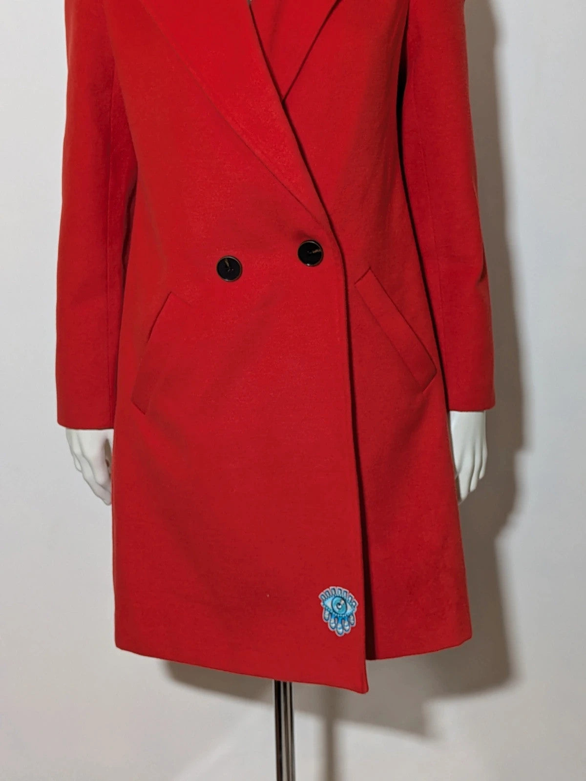Studio F red coat with black button closure and gold logo tag on collar.