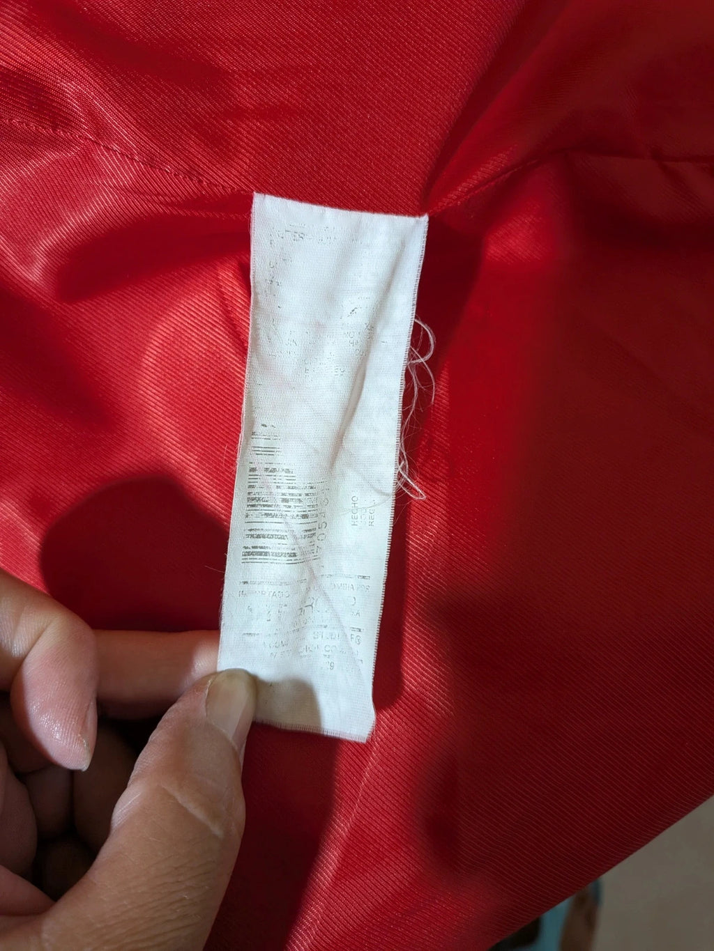 Studio F red coat with black button closure and gold logo tag on collar.