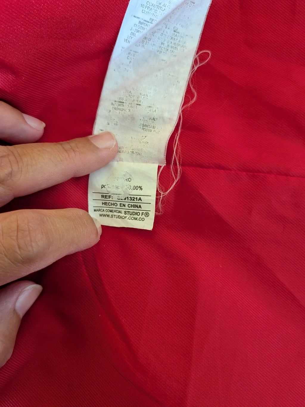 Studio F red coat with black button closure and gold logo tag on collar.