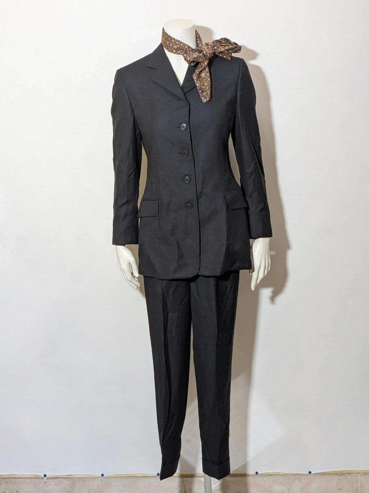 Synthesis Femme grey suit with structured jacket, four-button closure, and tailored trousers.