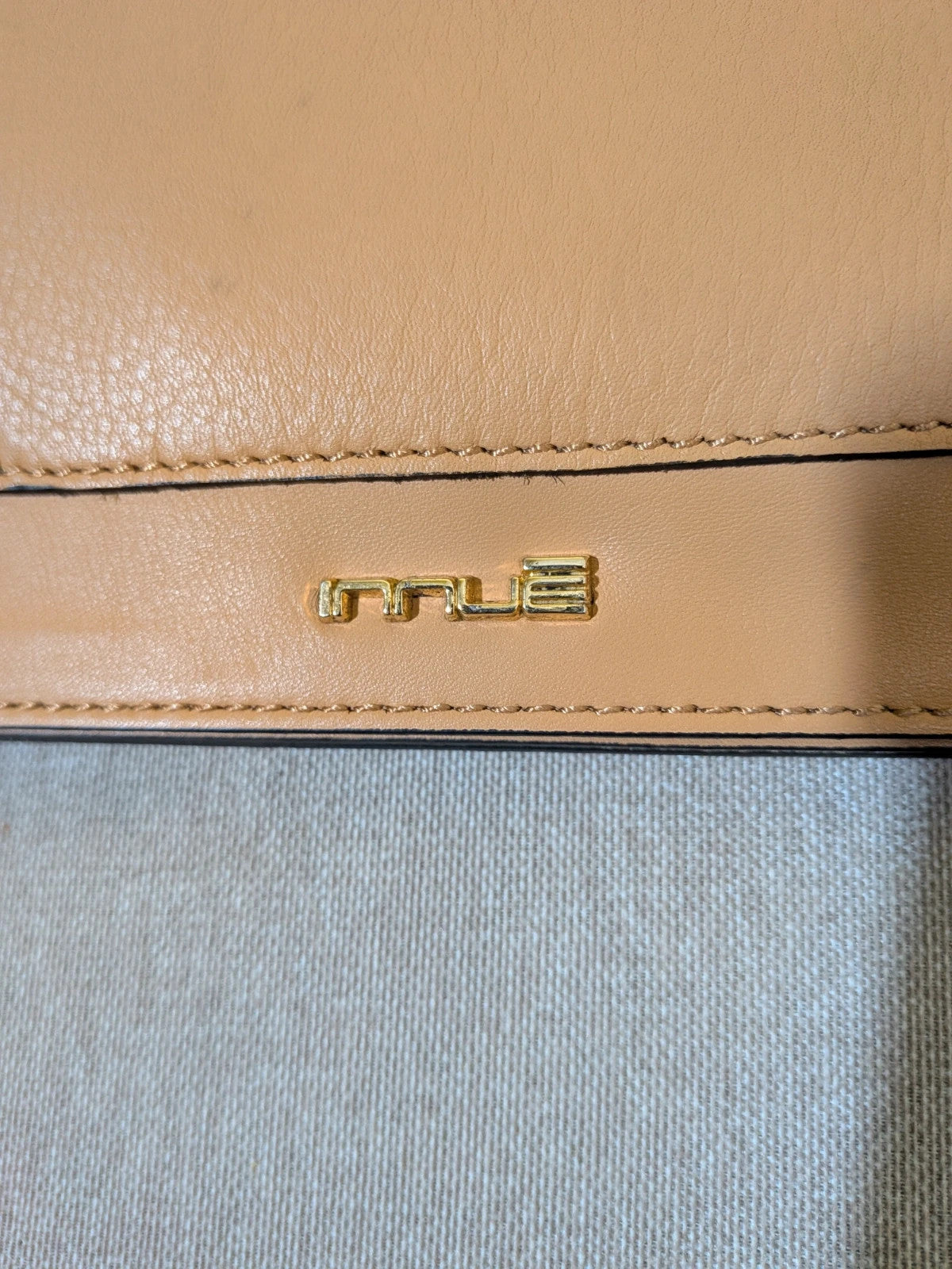 Innuè beige genuine leather shoulder bag with gold hardware and decorative buckles.