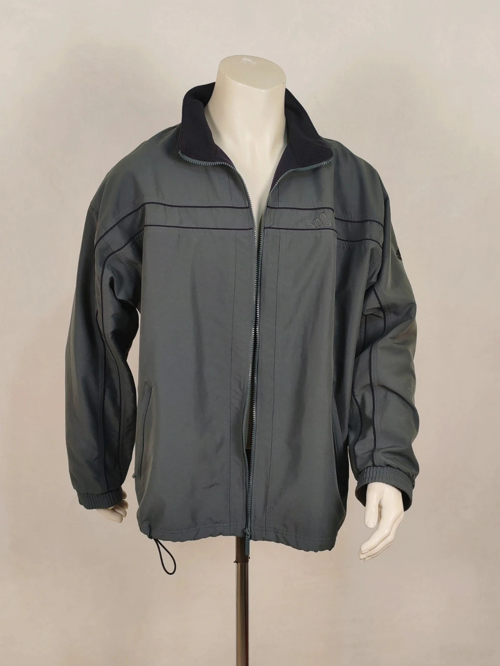 Adidas grey track jacket, high collar, zip closure, tonal details, vintage 90s style.