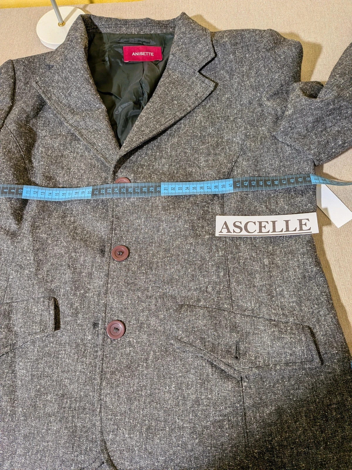 Anisette grey skirt suit with three-button blazer and knee-length skirt, tweed texture.