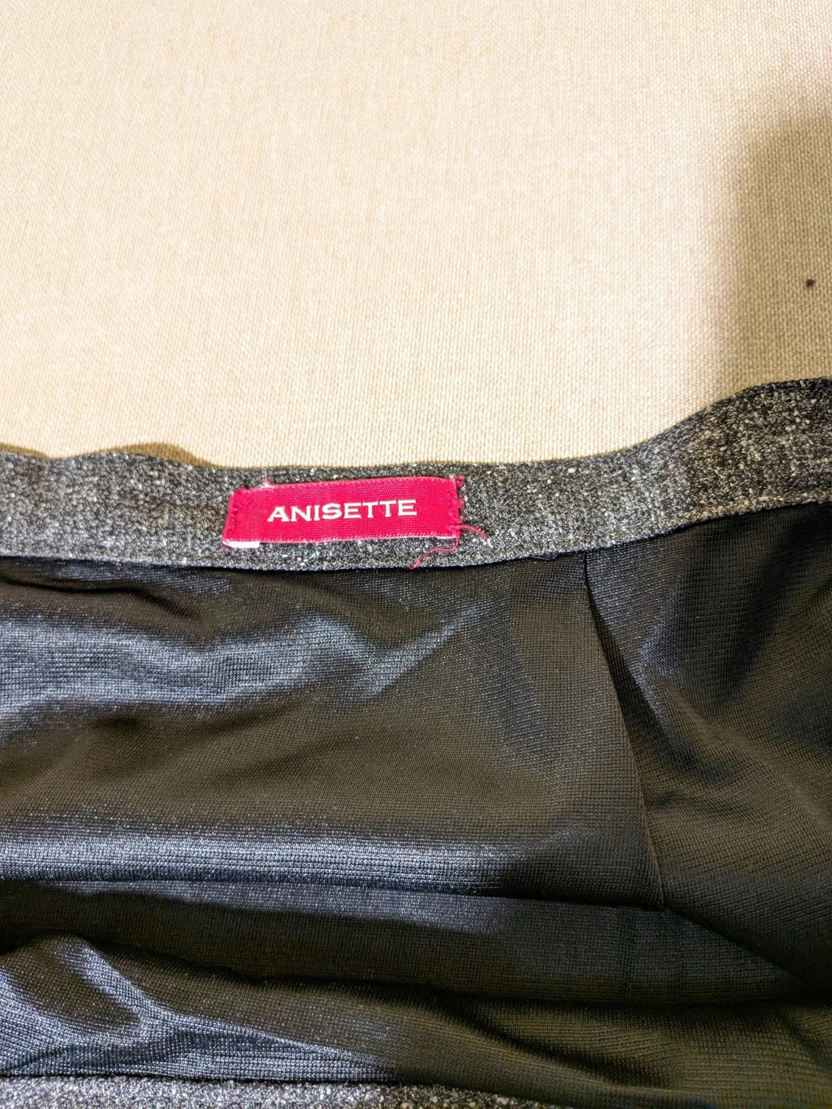 Anisette grey skirt suit with three-button blazer and knee-length skirt, tweed texture.
