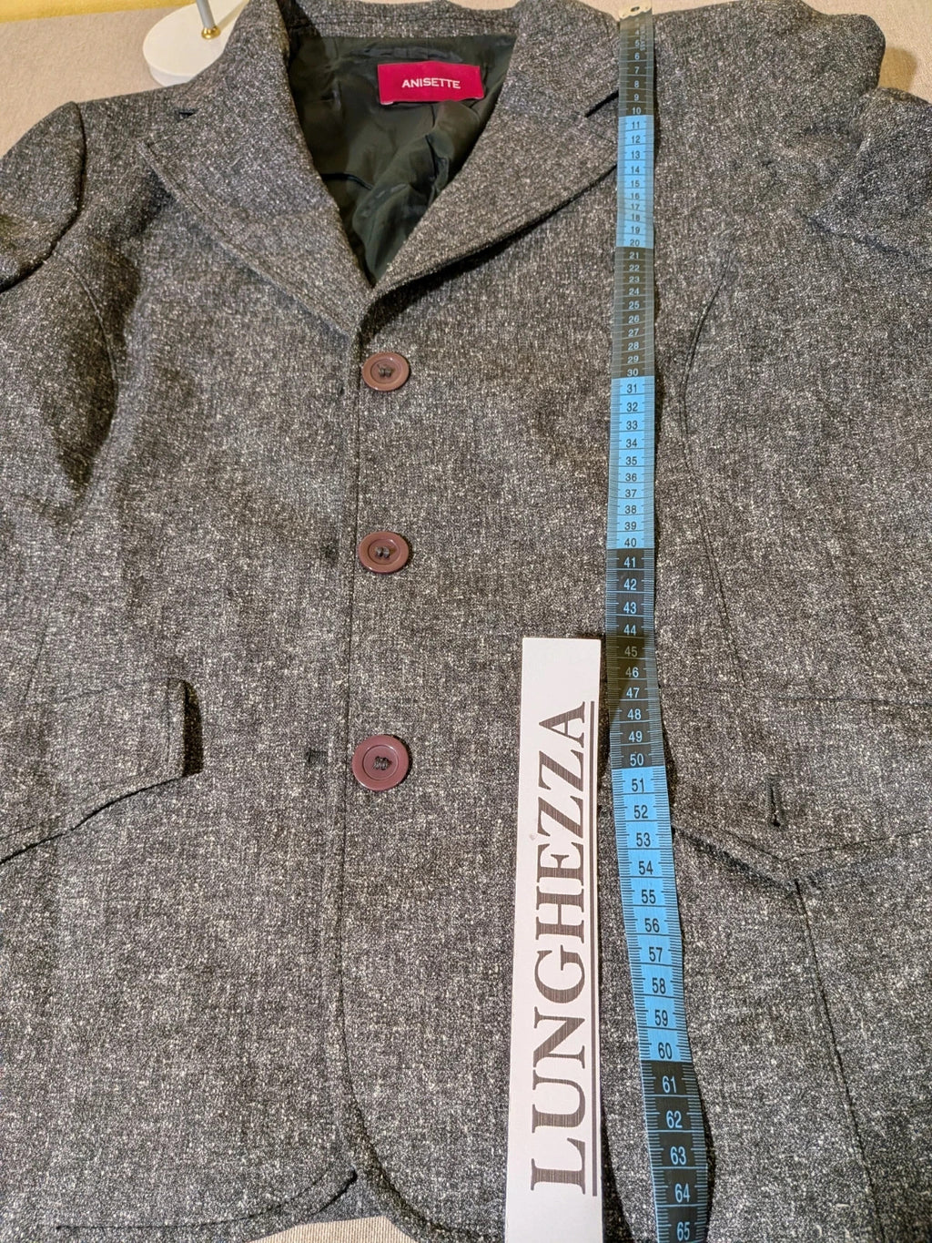Anisette grey skirt suit with three-button blazer and knee-length skirt, tweed texture.