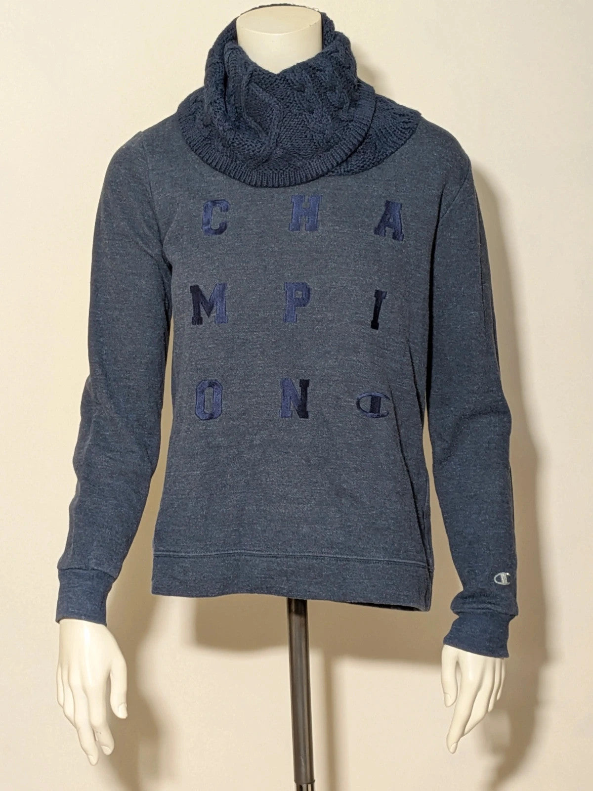 Champion navy turtleneck jumper with cable knit collar and embossed logo on front.