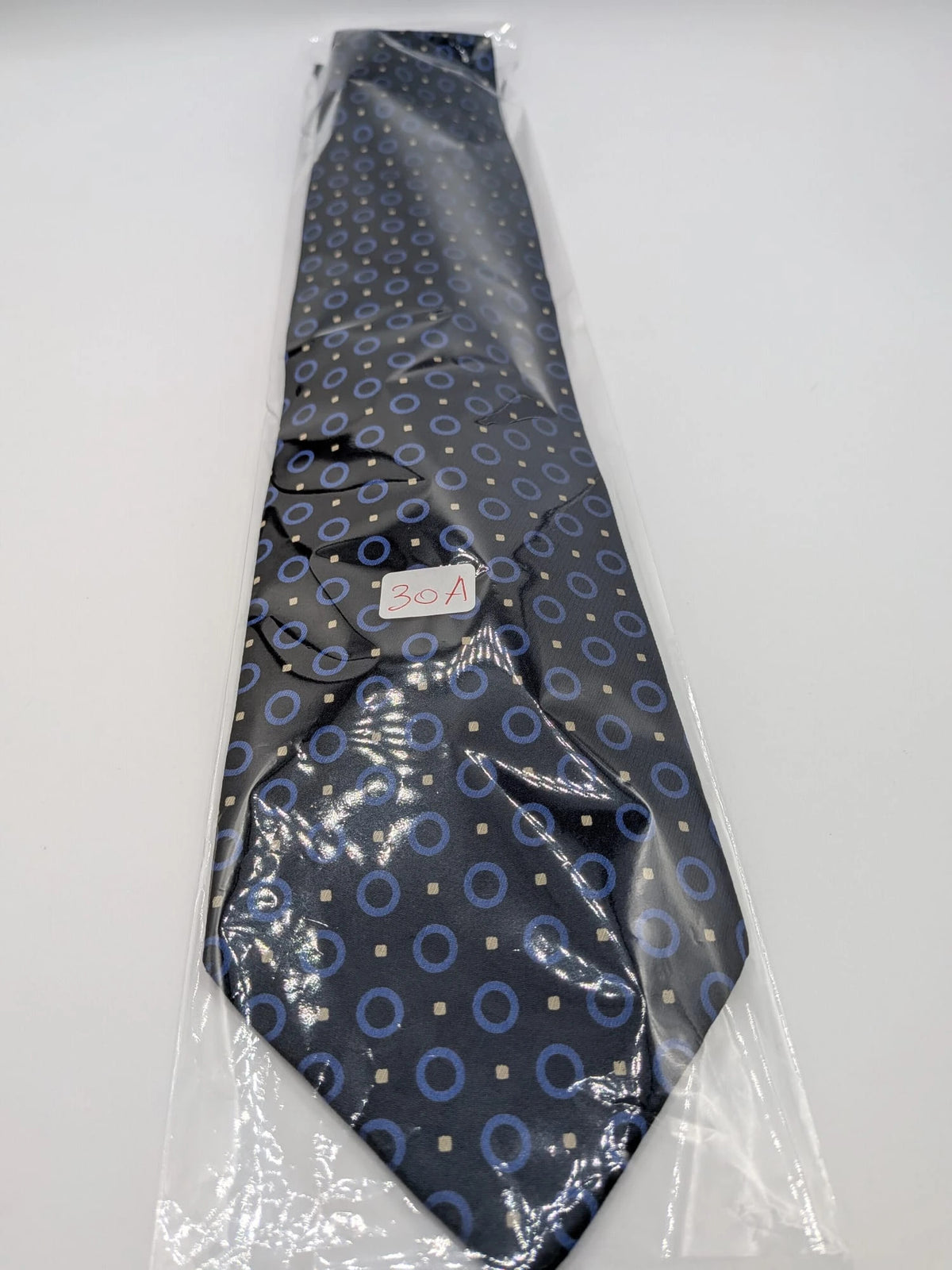 Milano navy tie geometric pattern with light blue rings and beige motifs, 100% silk.