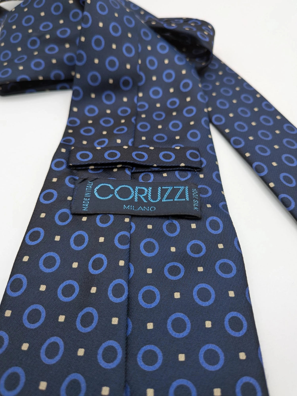 Milano navy tie geometric pattern with light blue rings and beige motifs, 100% silk.