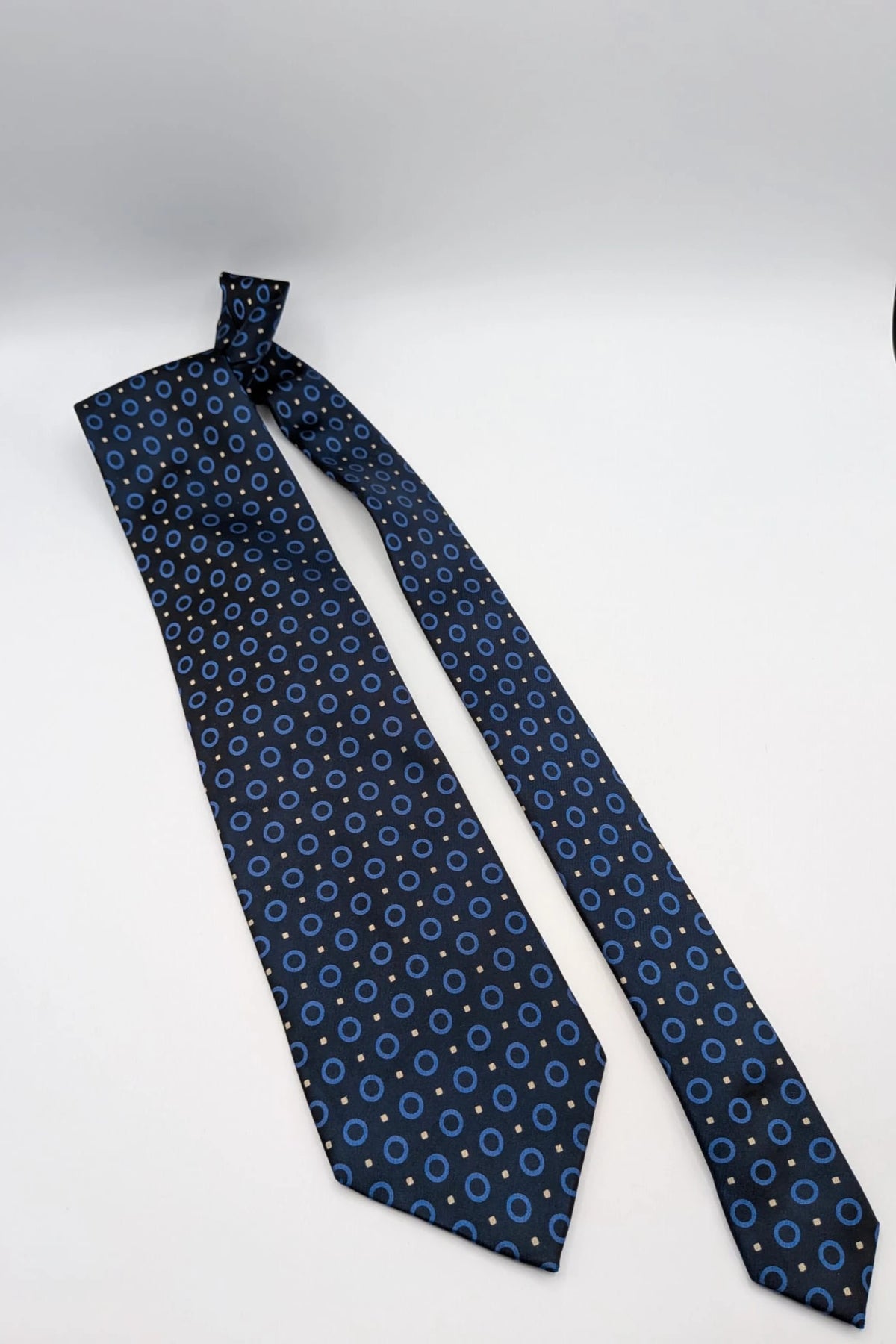 Milano navy tie geometric pattern with light blue rings and beige motifs, 100% silk.