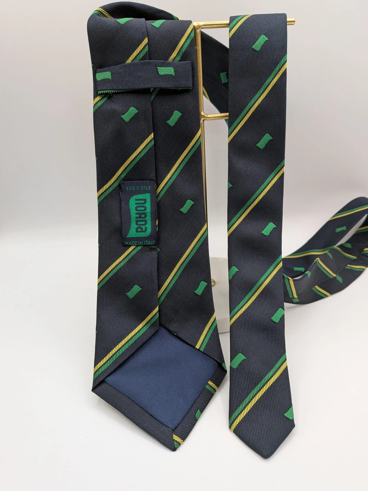 Norda tie navy blue with green and yellow diagonal stripes and geometric patterns.