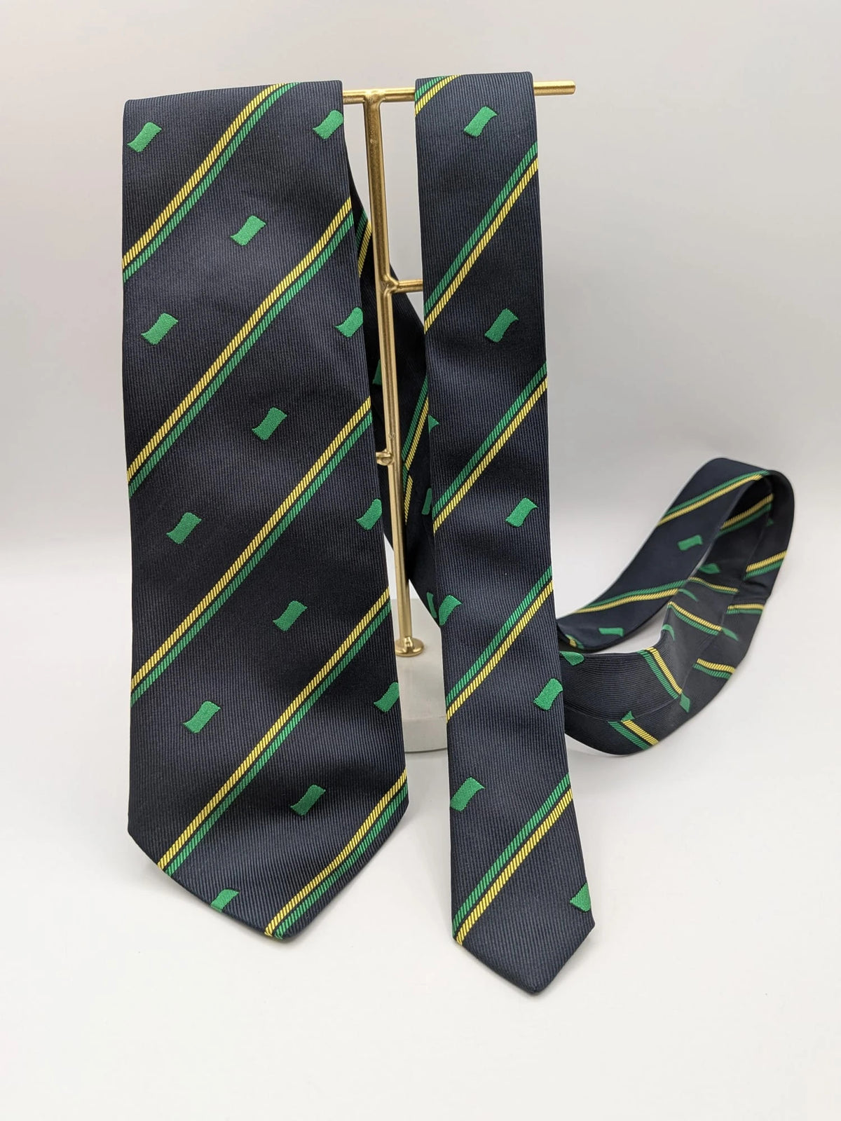 Norda tie navy blue with green and yellow diagonal stripes and geometric patterns.