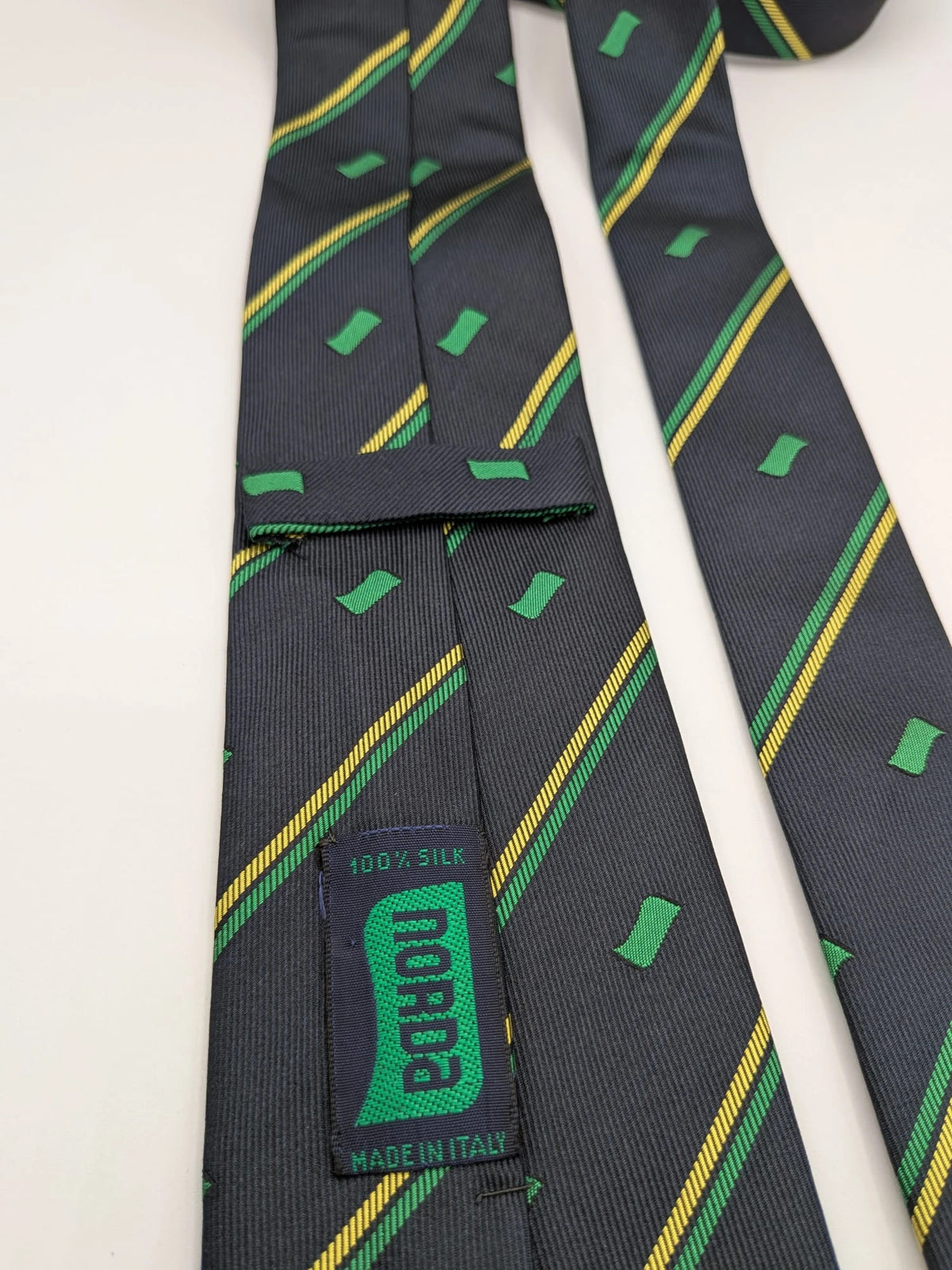Norda tie navy blue with green and yellow diagonal stripes and geometric patterns.