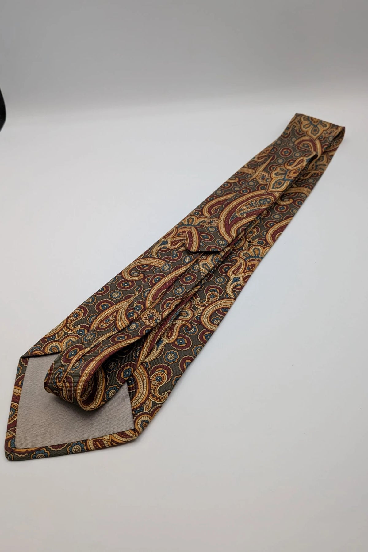 Uomo brown paisley tie in crèpe de chine with gold, blue, and burgundy patterns.