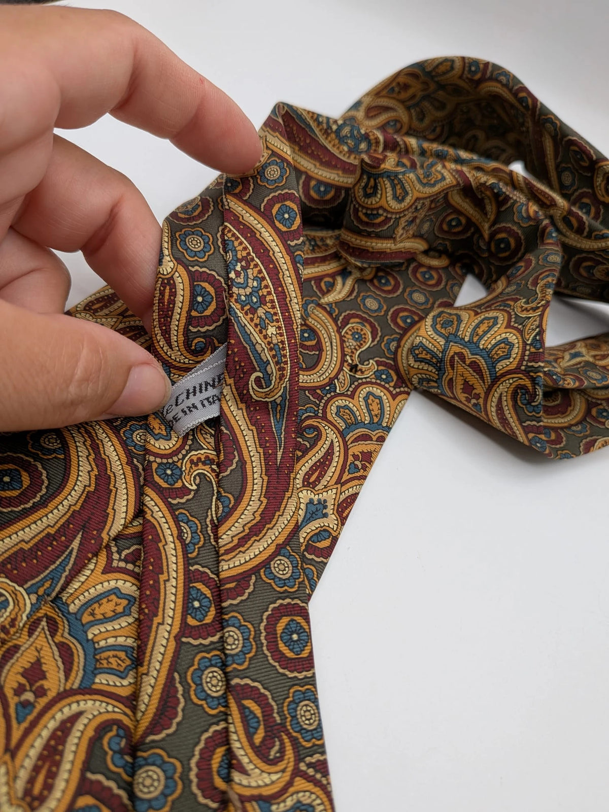 Uomo brown paisley tie in crèpe de chine with gold, blue, and burgundy patterns.