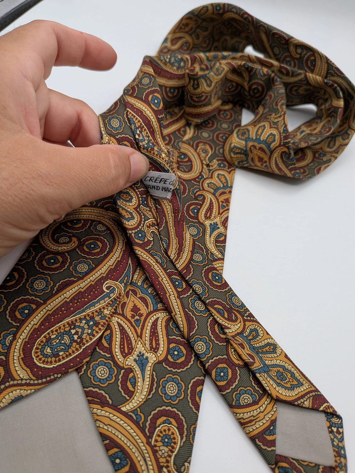 Uomo brown paisley tie in crèpe de chine with gold, blue, and burgundy patterns.