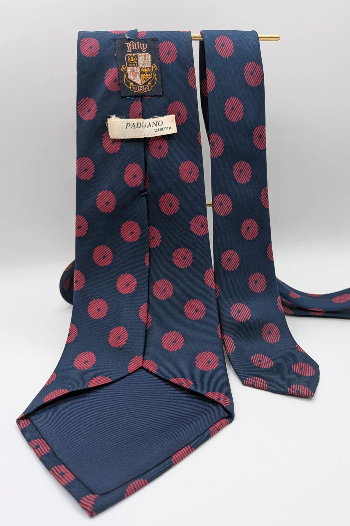 Uomo navy blue tie with red polka dots and diagonal stripes detail.