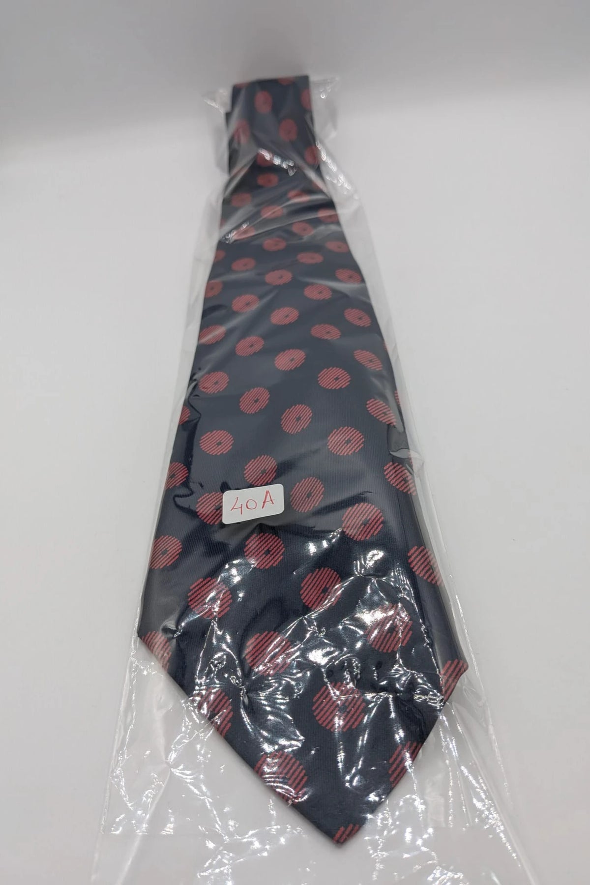 Uomo navy blue tie with red polka dots and diagonal stripes detail.