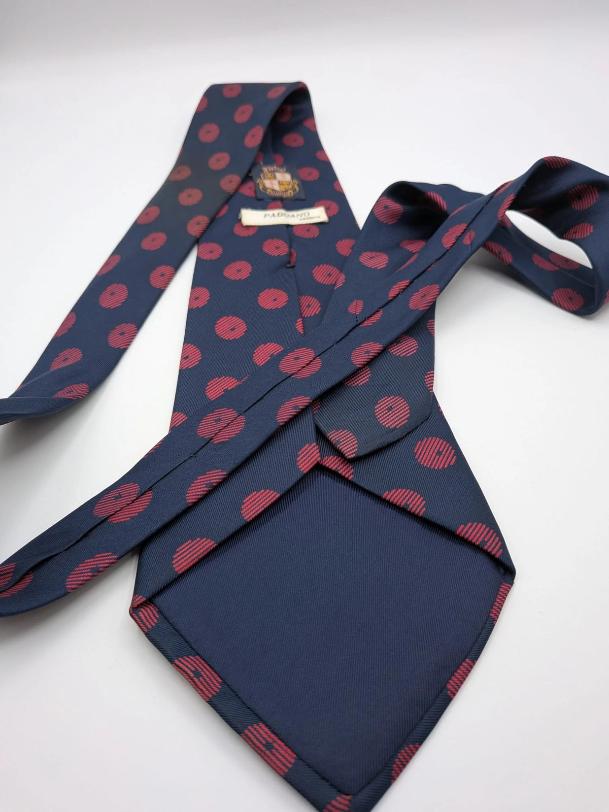 Uomo navy blue tie with red polka dots and diagonal stripes detail.