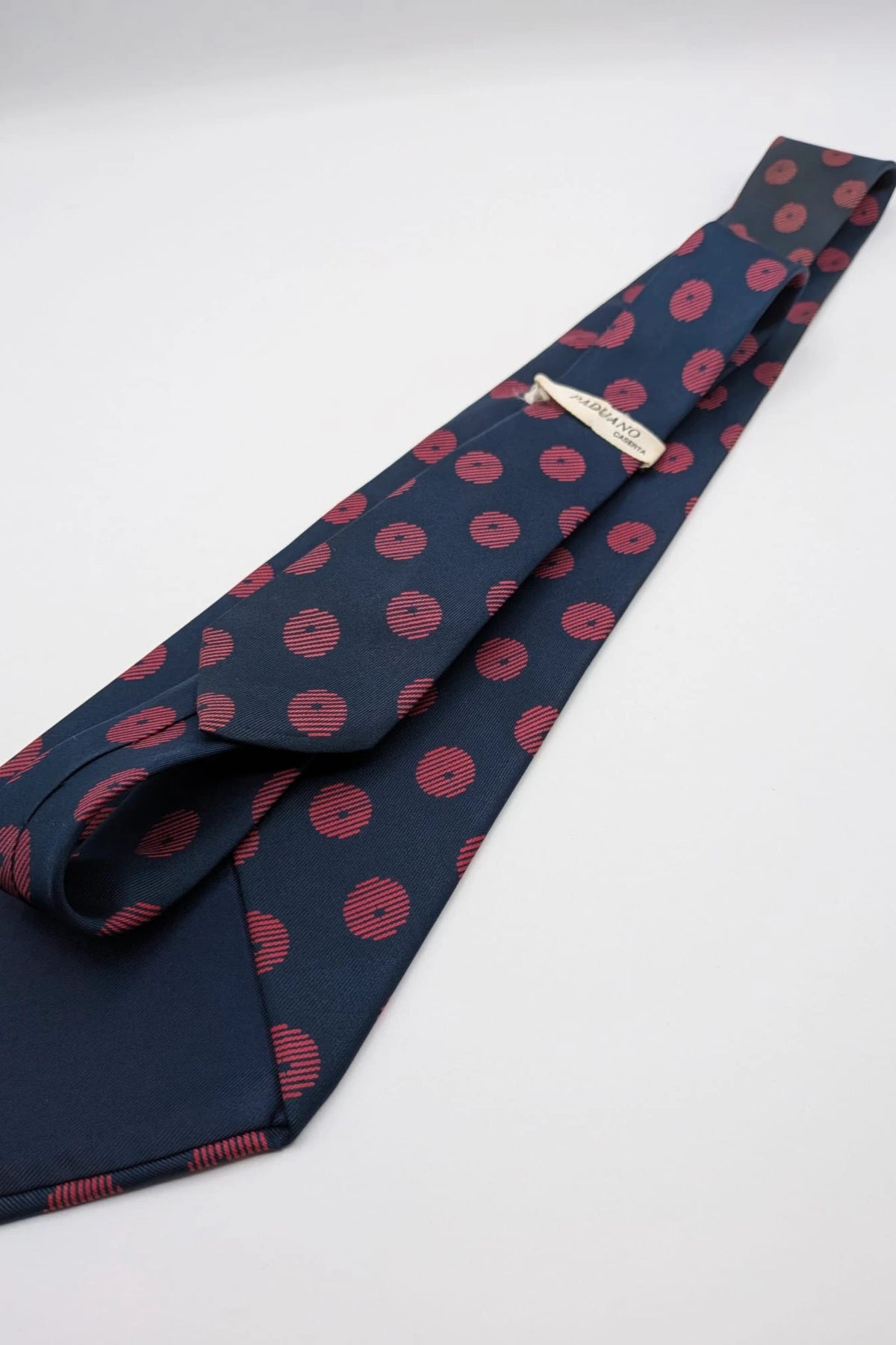 Uomo navy blue tie with red polka dots and diagonal stripes detail.
