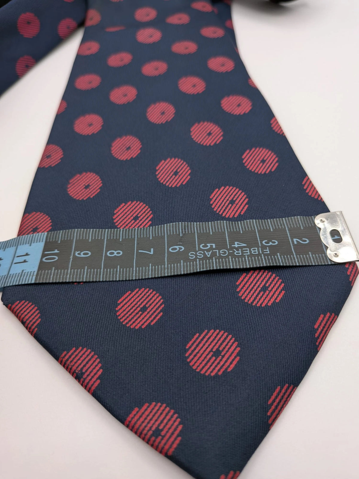 Uomo navy blue tie with red polka dots and diagonal stripes detail.