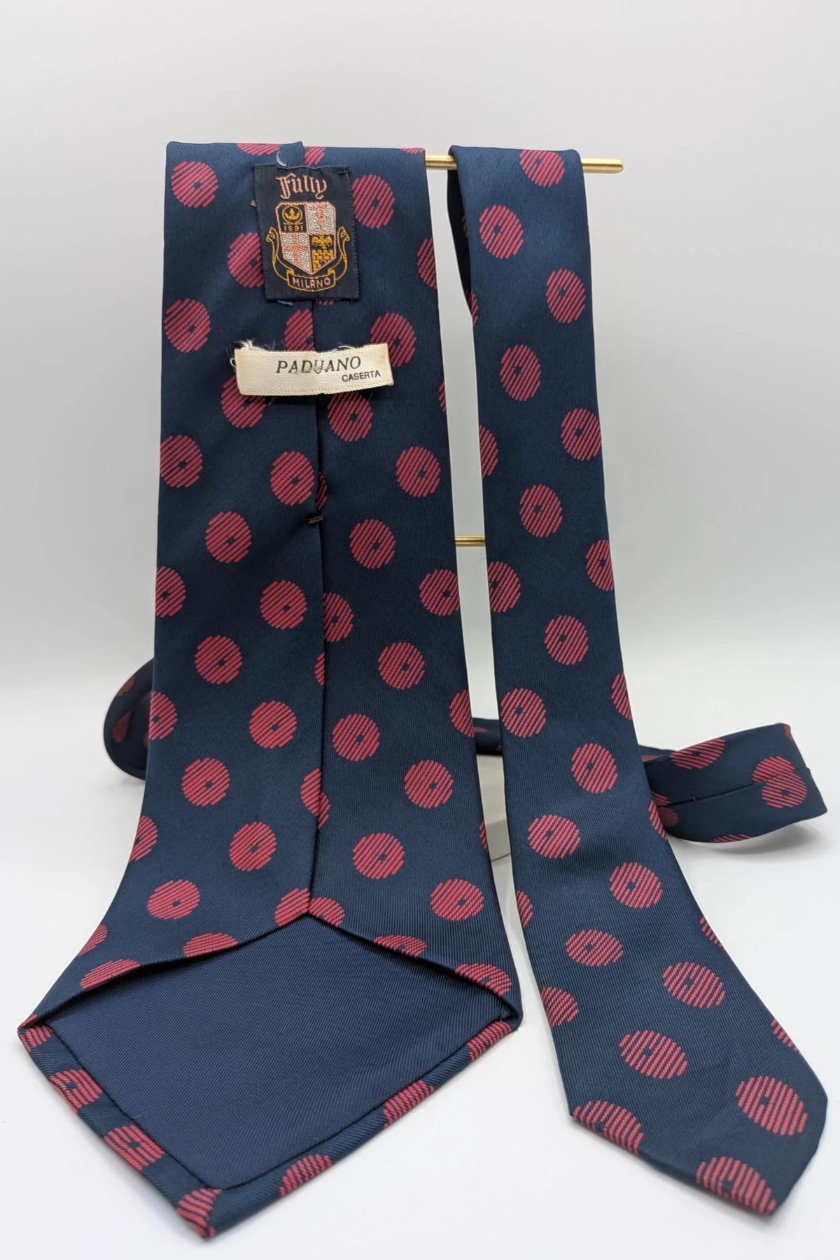 Uomo navy blue tie with red polka dots and diagonal stripes detail.