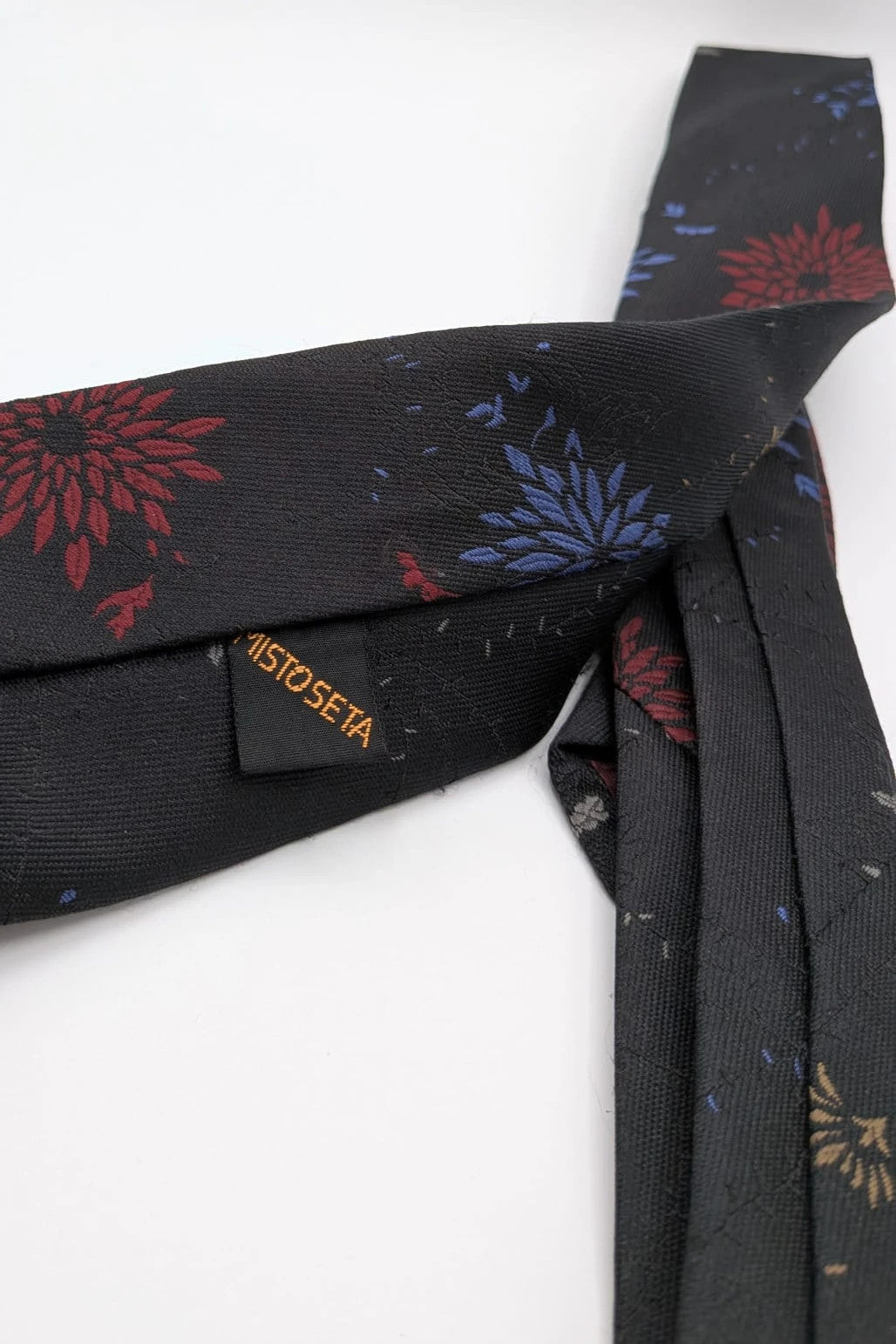 Uomo black tie with red and blue floral pattern, "Misto Seta" label, Made in Italy.