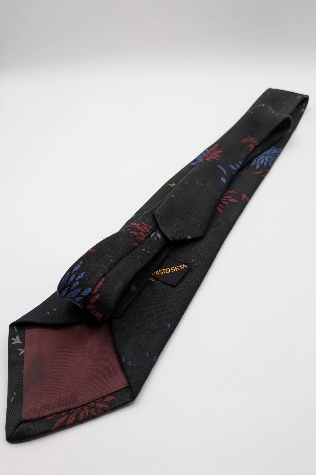 Uomo black tie with red and blue floral pattern, "Misto Seta" label, Made in Italy.