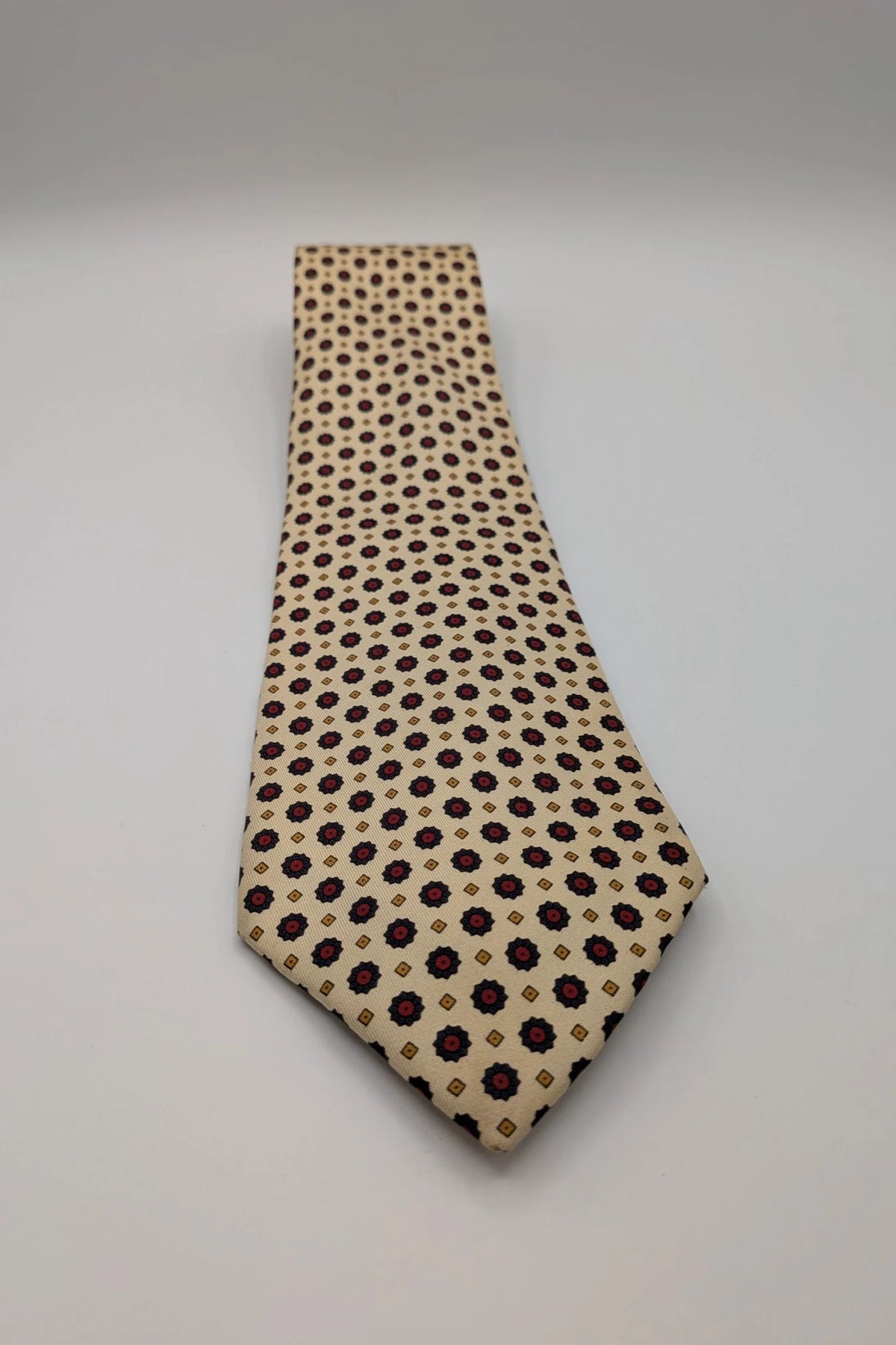 Uomo beige tie with floral pattern, blue and red flowers, geometric ochre details.
