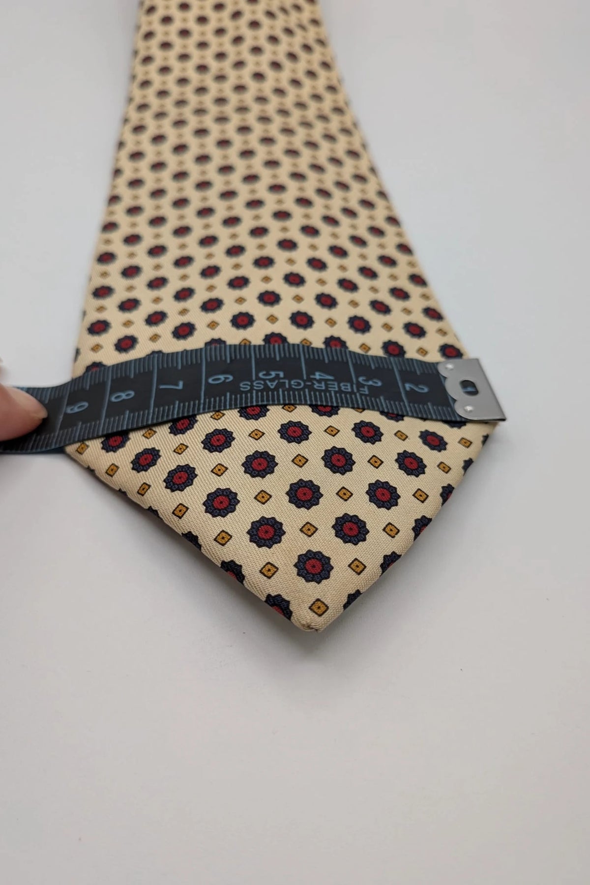 Uomo beige tie with floral pattern, blue and red flowers, geometric ochre details.