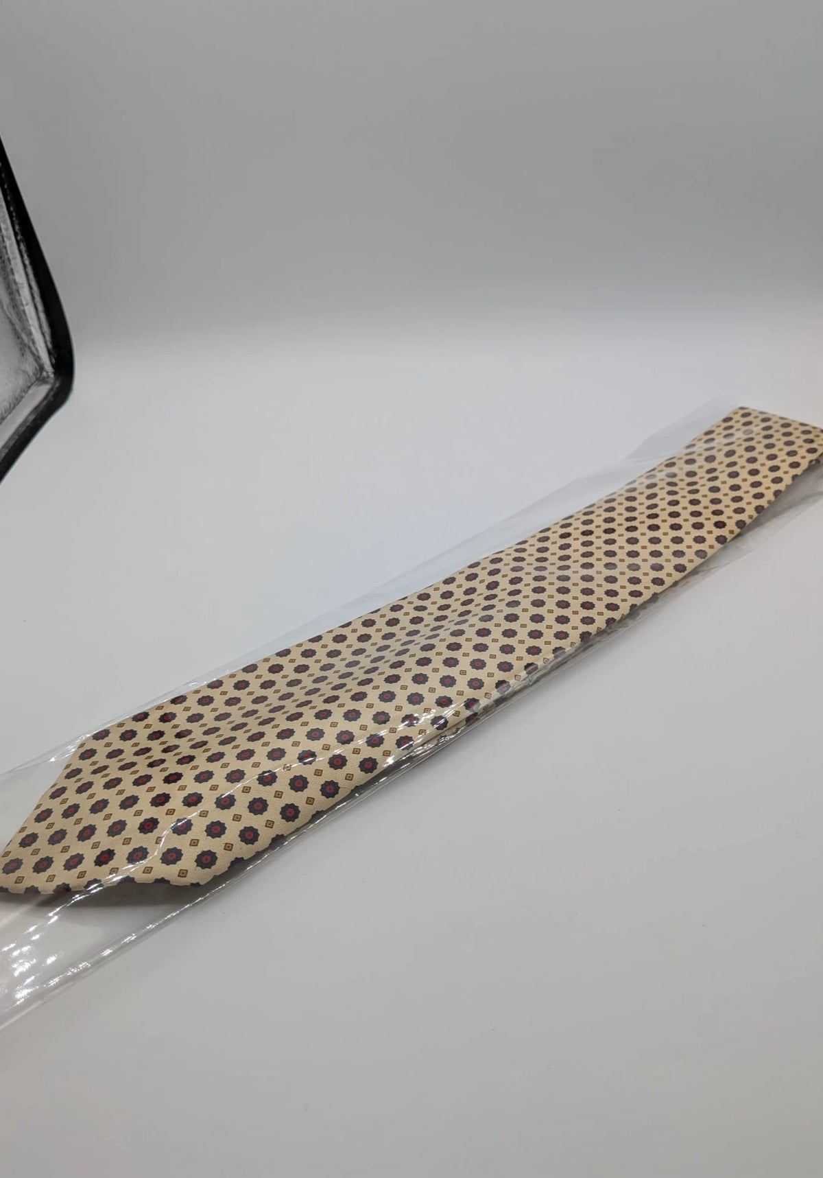 Uomo beige tie with floral pattern, blue and red flowers, geometric ochre details.