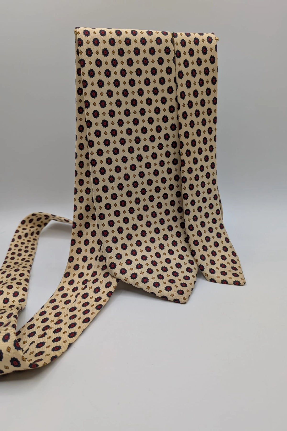 Uomo beige tie with floral pattern, blue and red flowers, geometric ochre details.