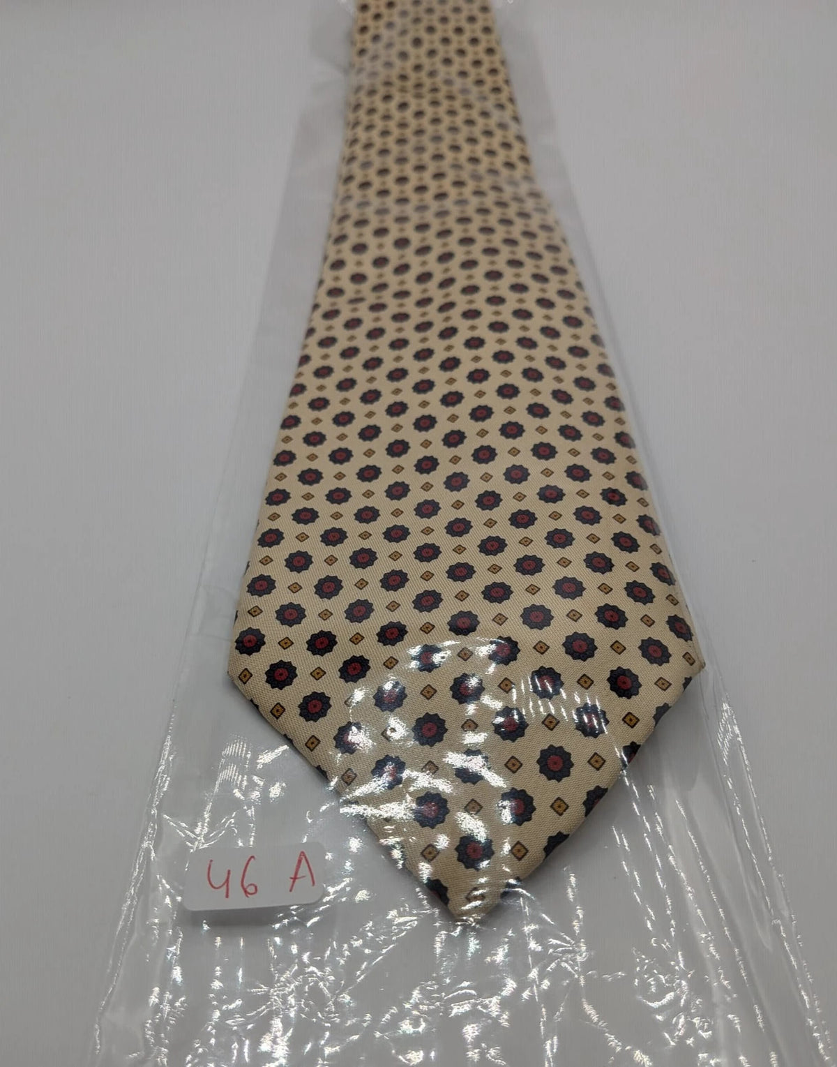 Uomo beige tie with floral pattern, blue and red flowers, geometric ochre details.
