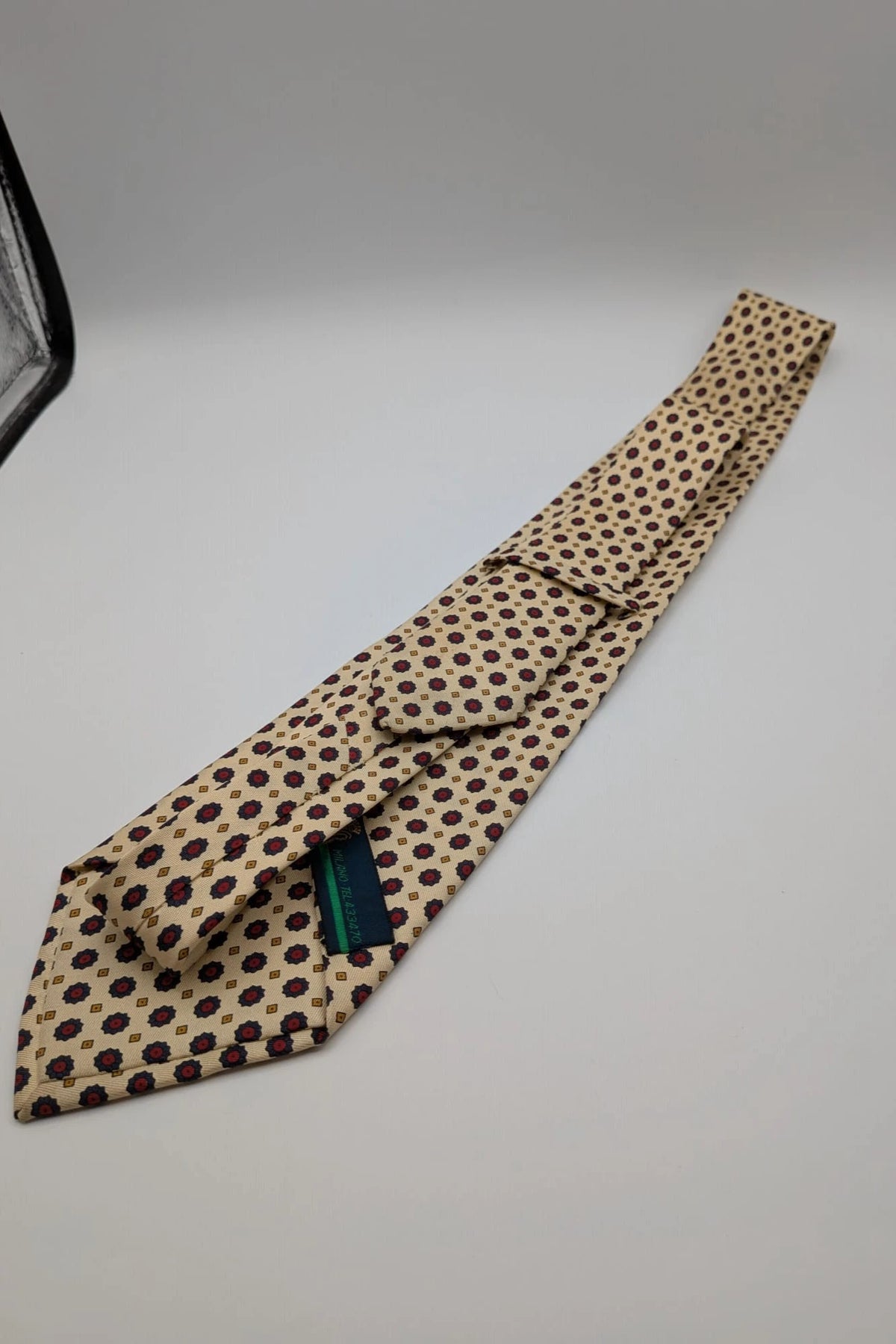 Uomo beige tie with floral pattern, blue and red flowers, geometric ochre details.